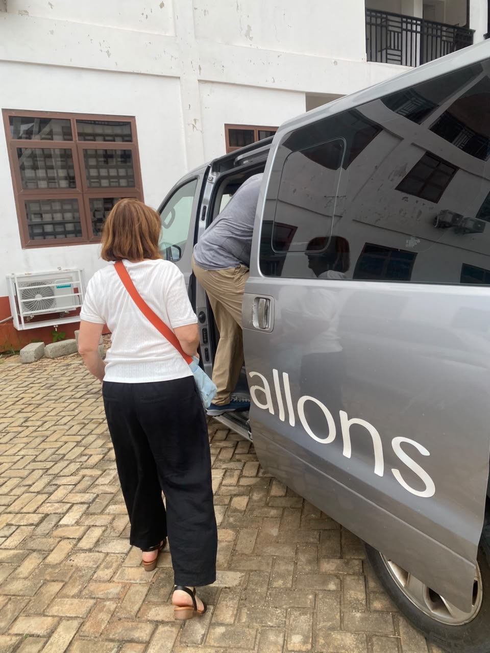 International travelers boarding a branded Allons van