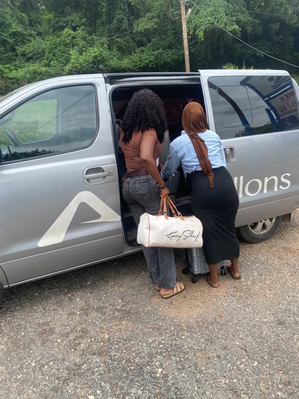 Two customers loading bags into an Allons van on the road