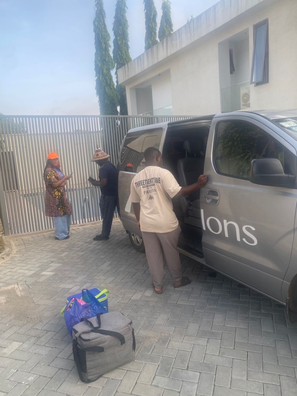 Driver loading luggage into an Allons van at a residence